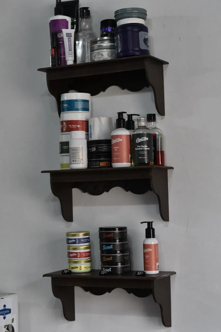 Prateleira de três níveis com pomadas, tônicos e loções pós-barba